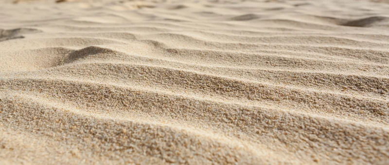 Close-up of rippled dry beach sand under sunlight
