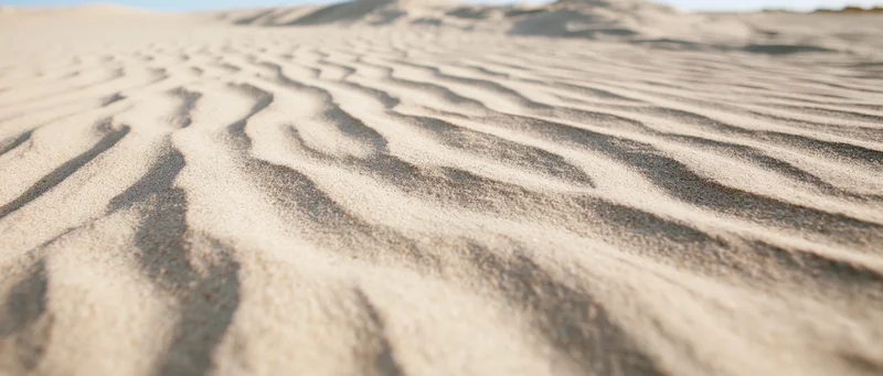 Close-up of rippled dry sand on a beach under bright light