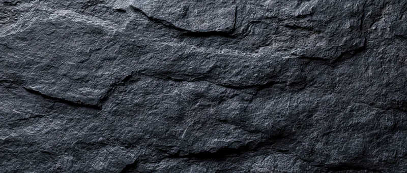 Close-up of dark slate stone wall surface with natural cracks and layers