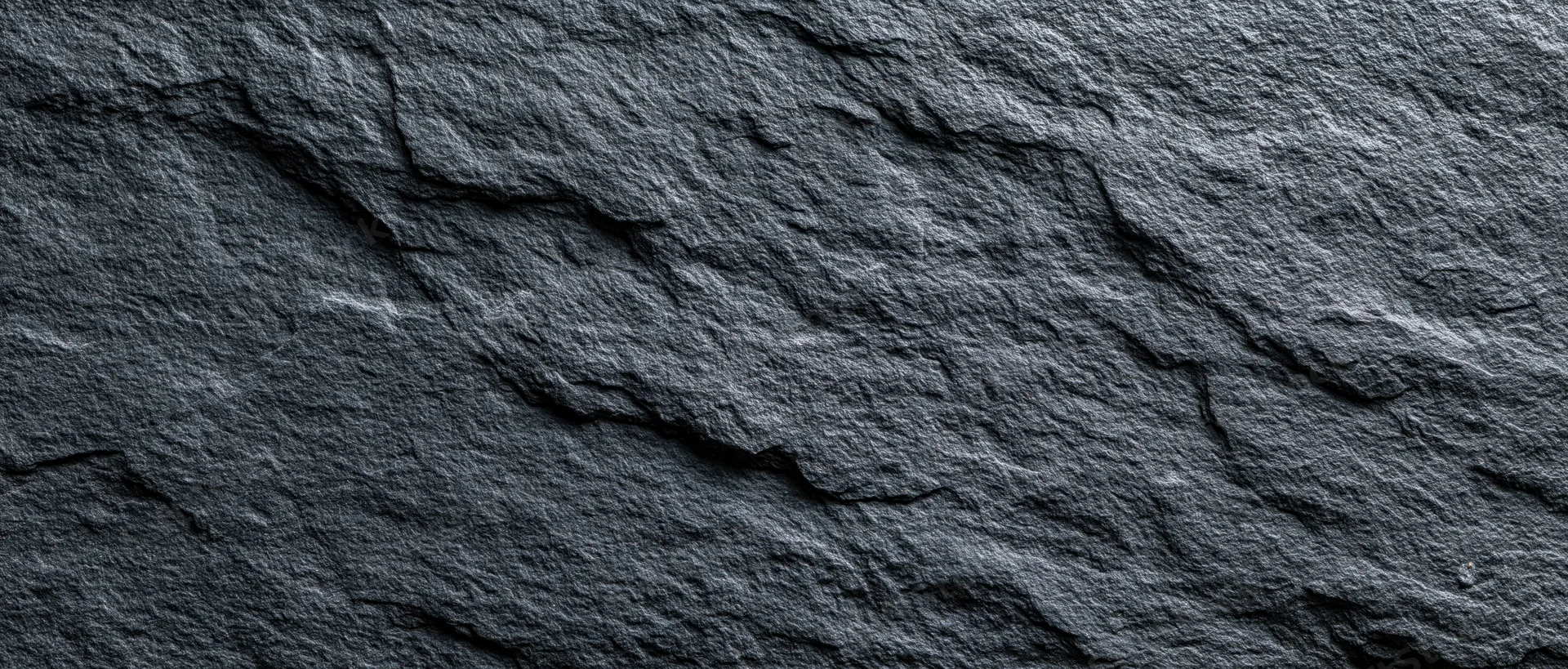 Close-up of dark slate stone wall surface with natural cracks and texture