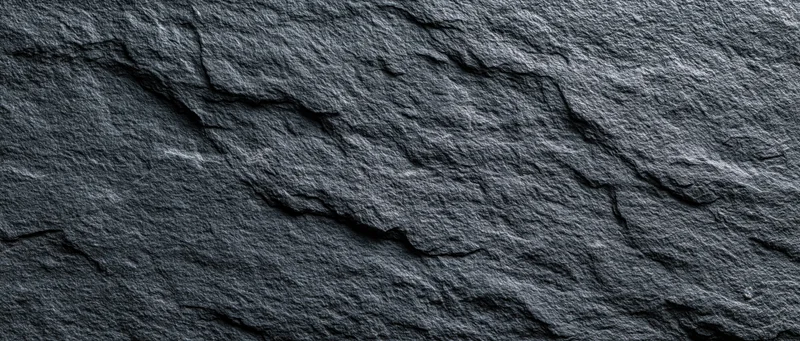 Close-up of dark slate stone wall surface with natural cracks and texture