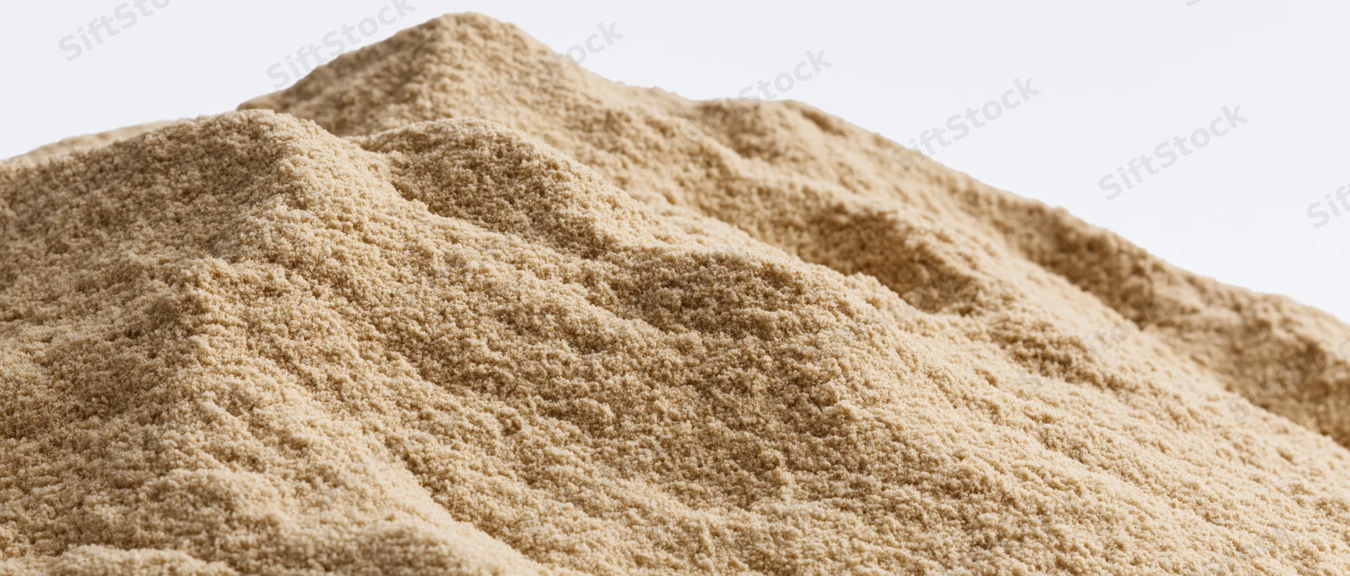 Close-up of a dry sand mound with uneven ridges and textured surface against a plain background