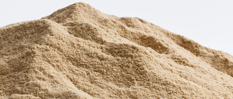 Close-up of a dry sand mound with uneven ridges and textured surface against a plain background