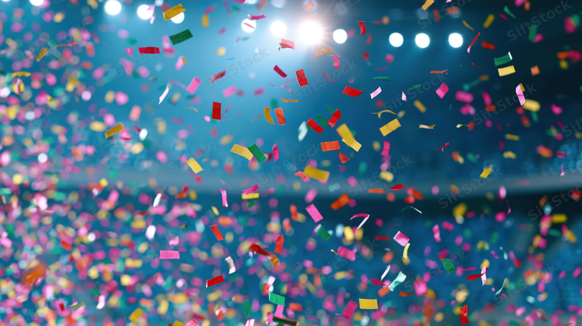Colorful paper confetti falling in mid-air inside a lit stage venue