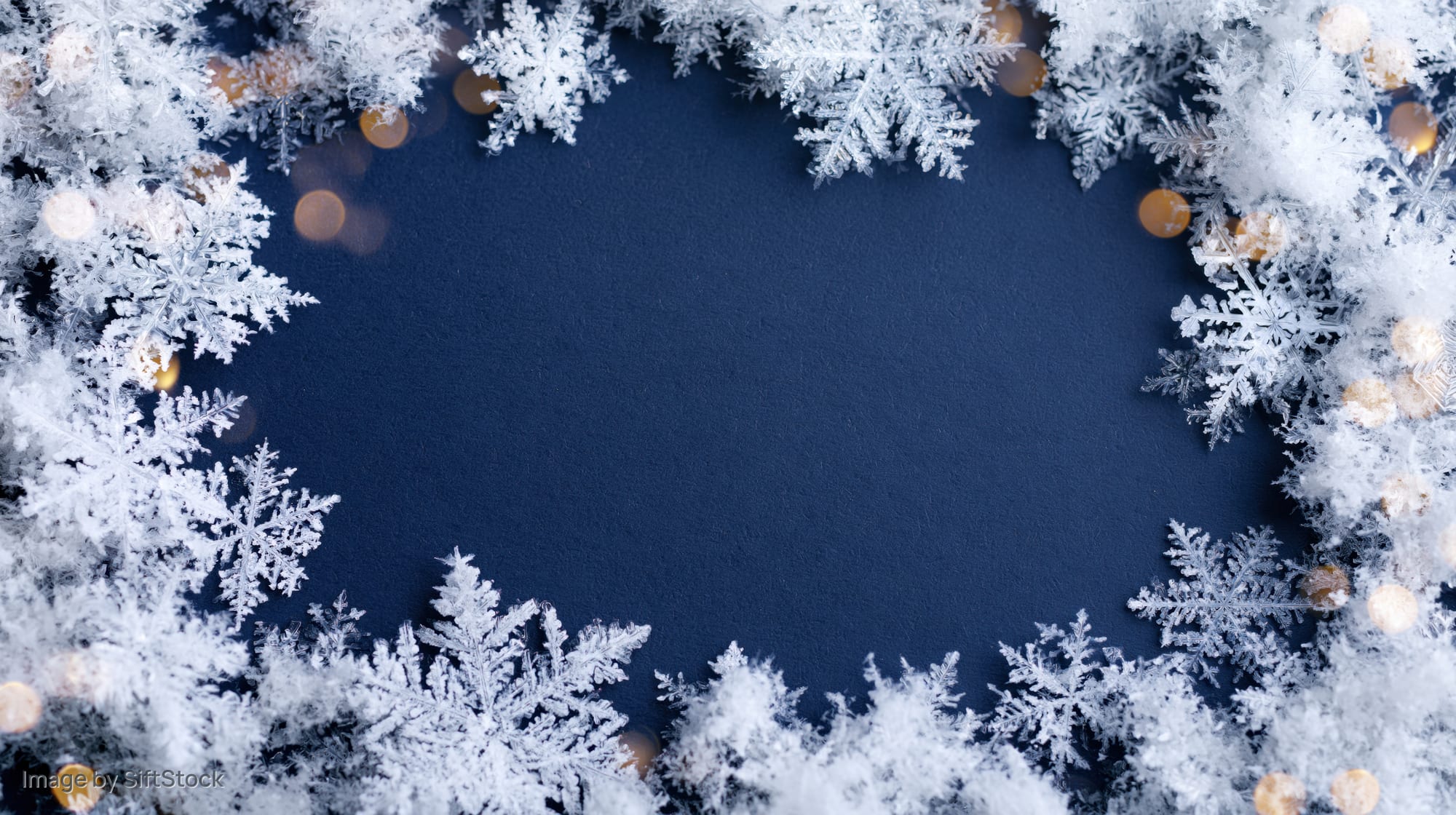 Frosty snowflake frame border on blue background with golden bokeh lights and copyspace