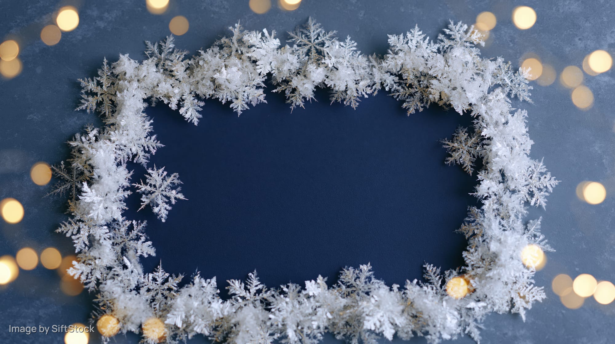 White frost snowflake frame border on blue background with golden bokeh lights