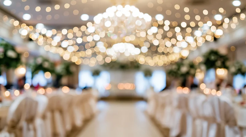 Blurred interior of a wedding reception with golden bokeh lights and white table settings