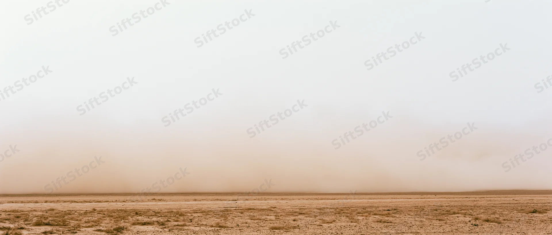 Dense dust cloud billowing low across dry desert floor wide