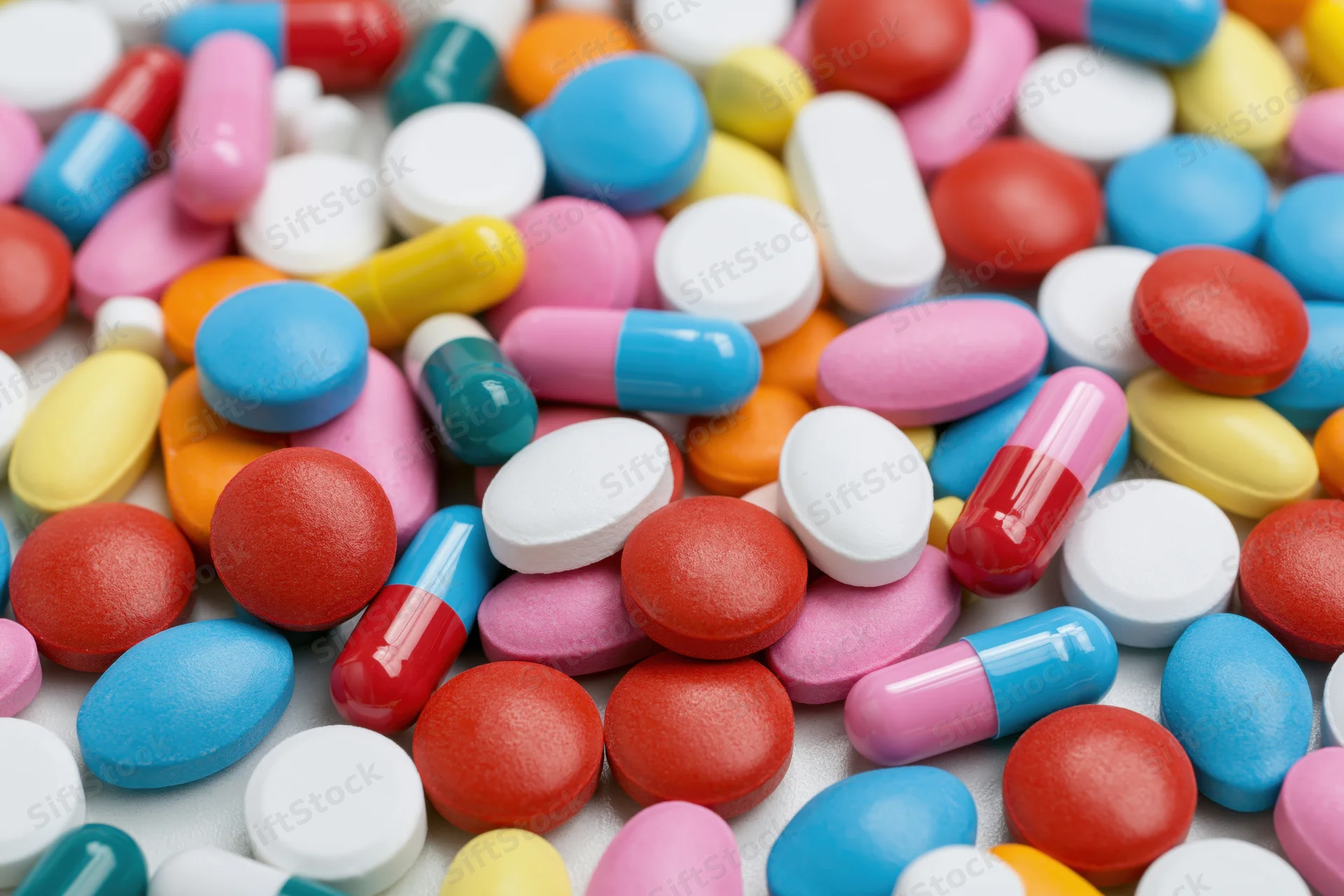 Assorted pharmaceutical pills and capsules scattered on a white surface