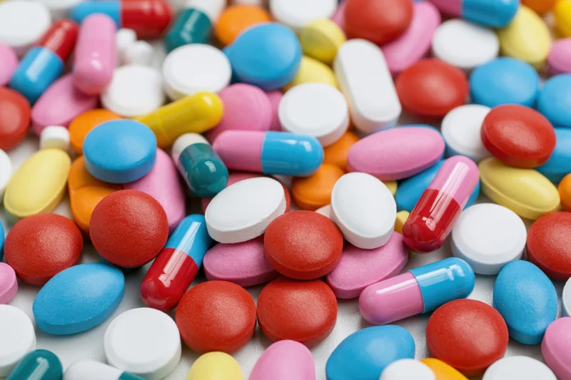 Assorted pharmaceutical pills and capsules scattered on a white surface