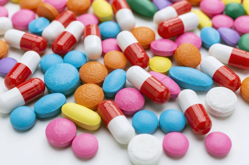 Scattered colorful pills and capsules on white surface
