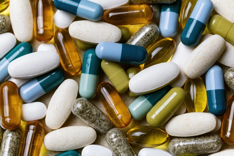 Assorted medication capsules and tablets scattered on a surface