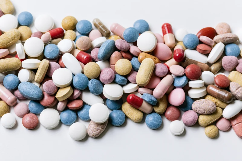 Assorted prescription pills and capsules scattered on a white surface