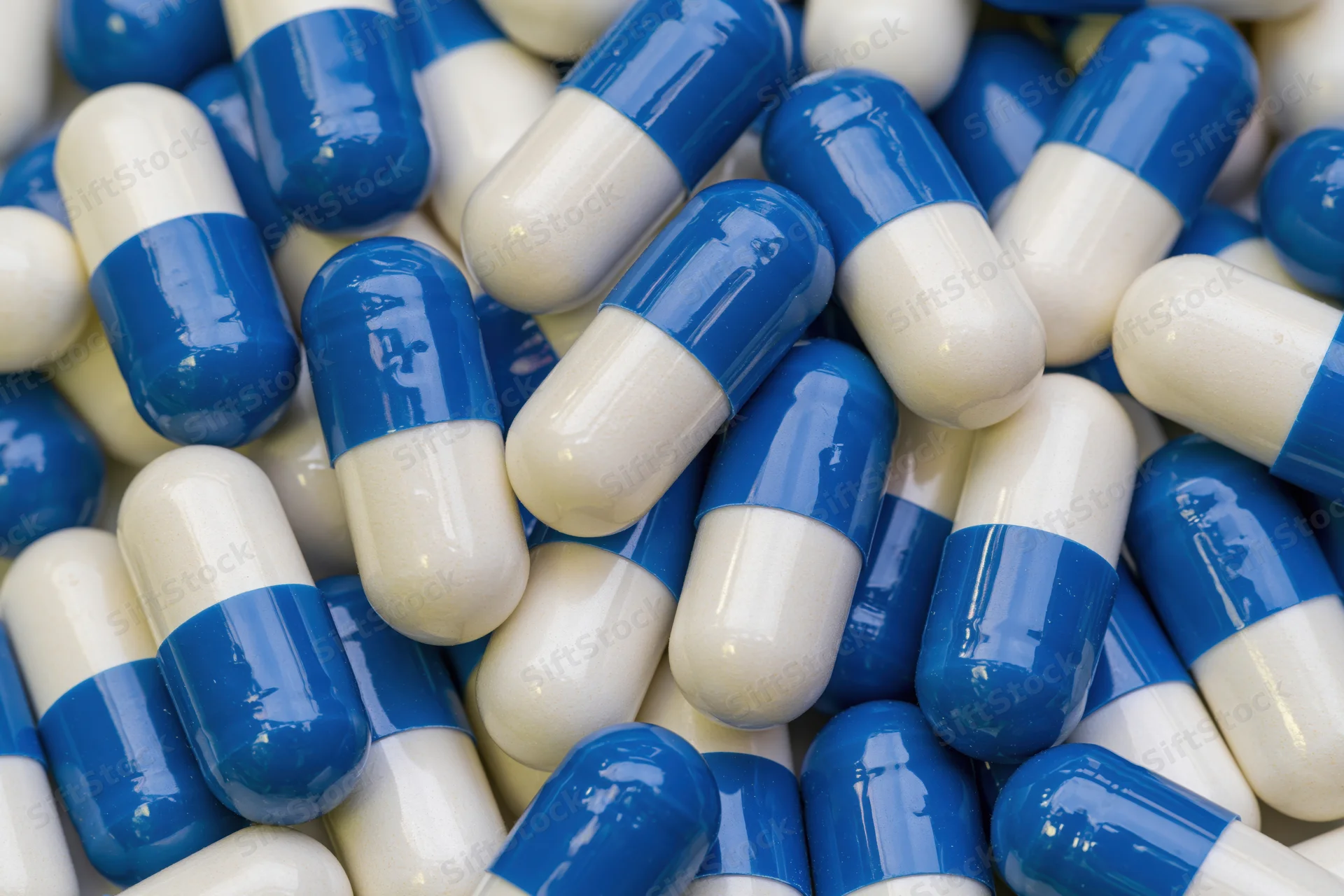 Blue and white gelatin capsules scattered in a pile