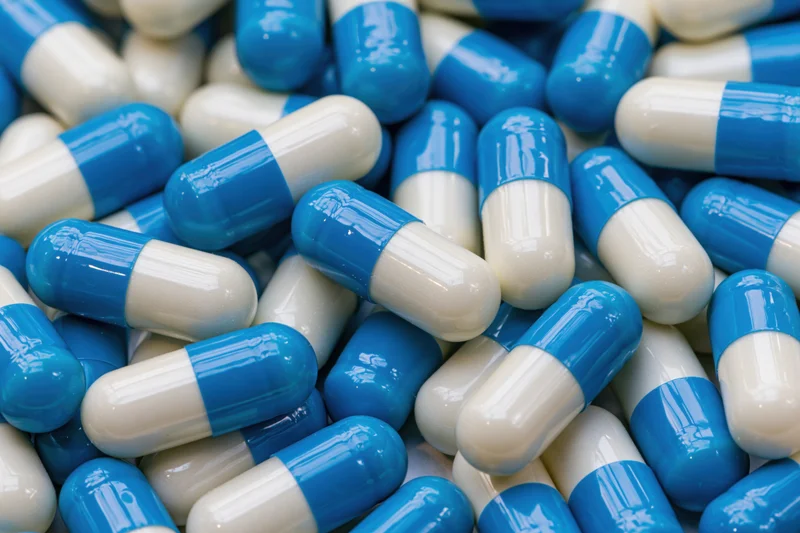Blue and white gelatin capsules scattered in a pile