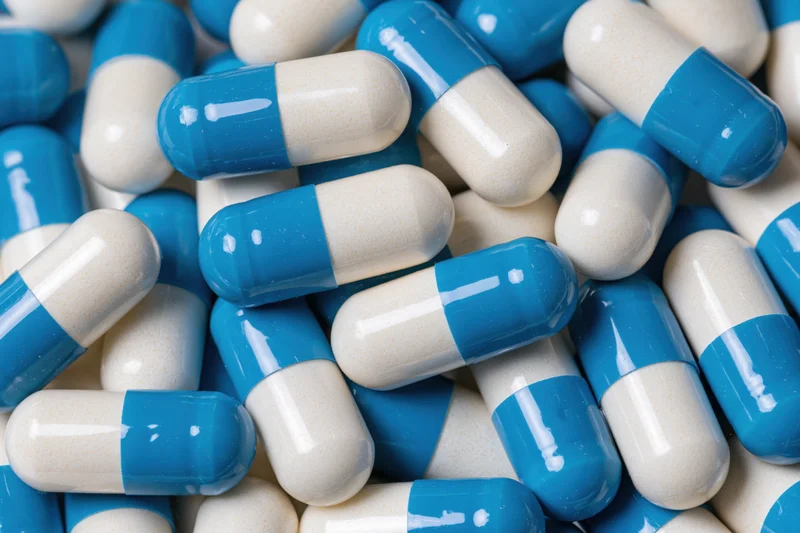 Blue and white gelatin capsules scattered in a pile