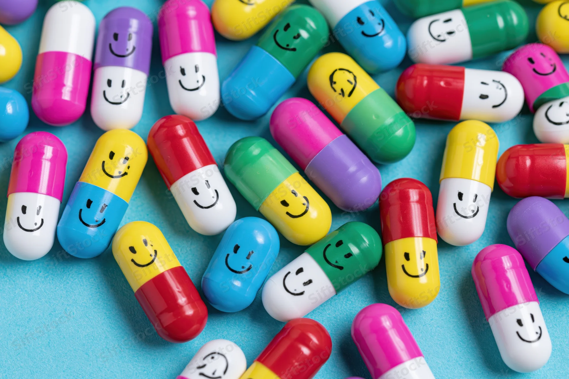 Colorful capsule pills with hand-drawn smiley faces scattered on a blue surface