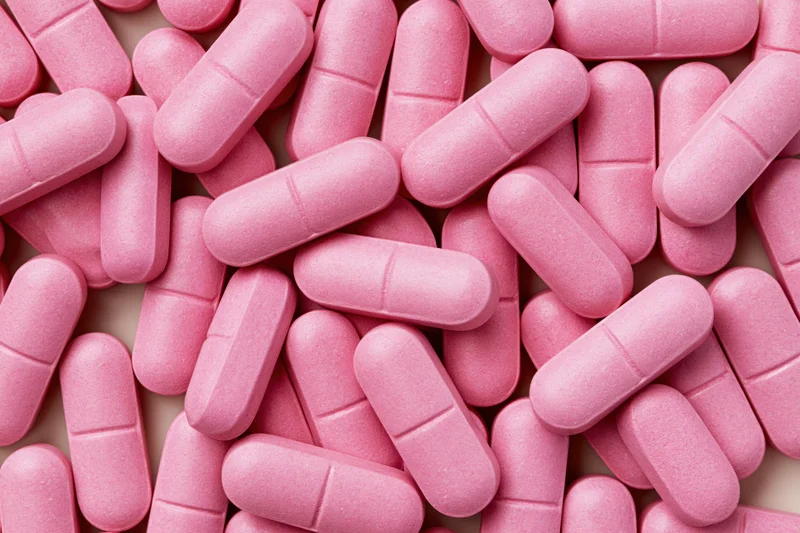 Scattered pink supplement tablets in close-up overhead view