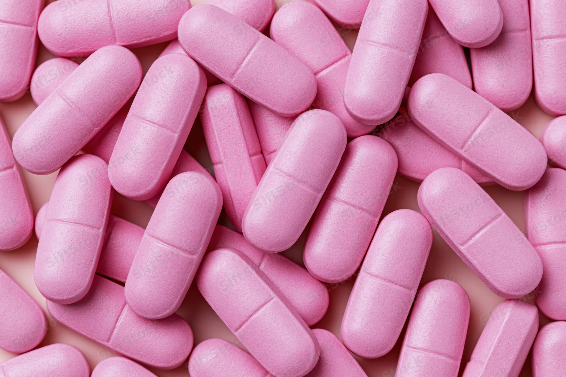 Pink supplement tablets scattered in close-up view