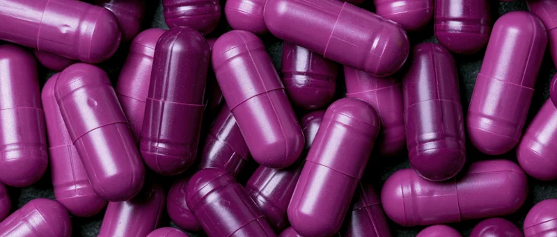 Purple gel capsules densely packed filling the frame