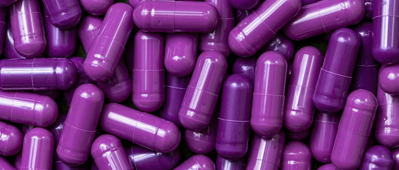 Purple gel capsules densely packed filling the frame