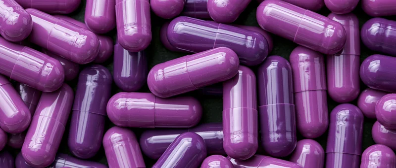 Purple gel capsules densely packed in a close-up view