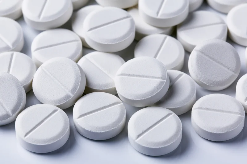 Close-up of round white pharmaceutical tablets with score lines on a white surface