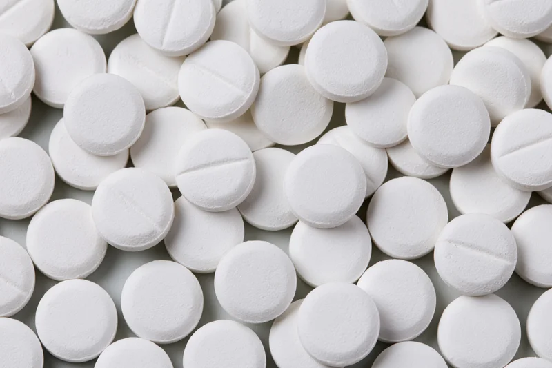 Scattered white round pharmaceutical tablets on a flat surface