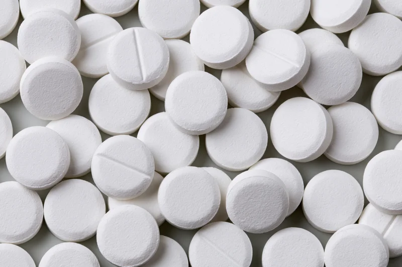 Scattered white round pharmaceutical tablets on a flat surface