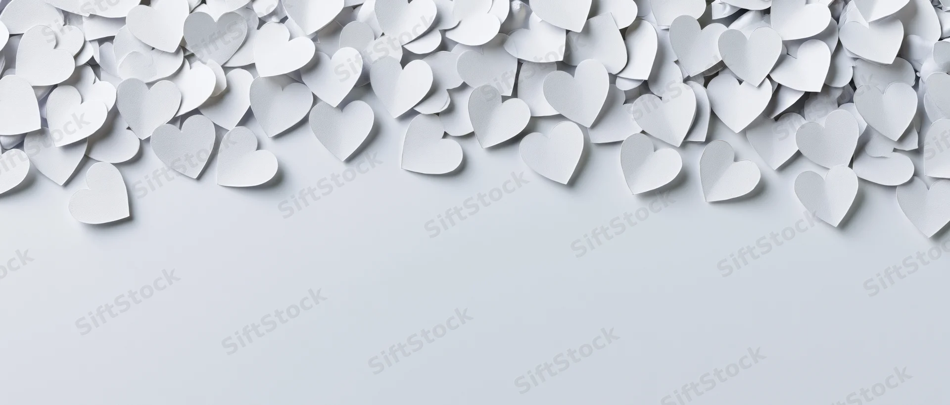 White paper hearts scattered across top of frame leaving copyspace below