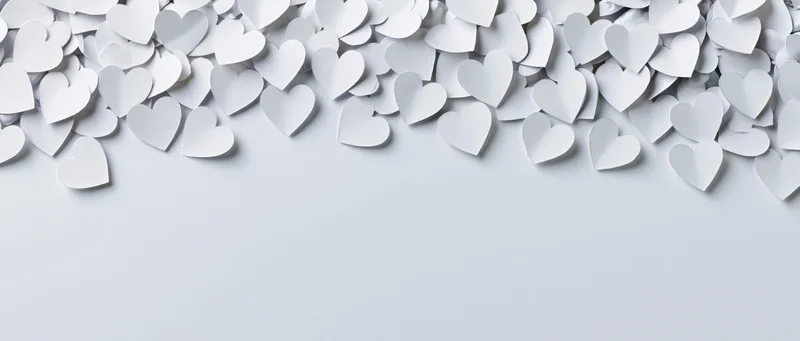 White paper hearts scattered across top of frame leaving copyspace below