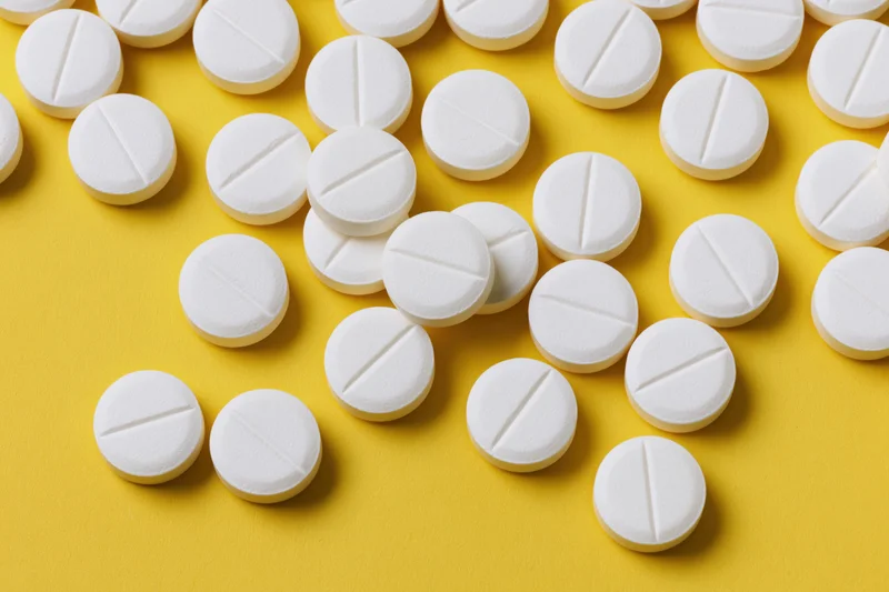 White round pharmaceutical tablets scattered on yellow background