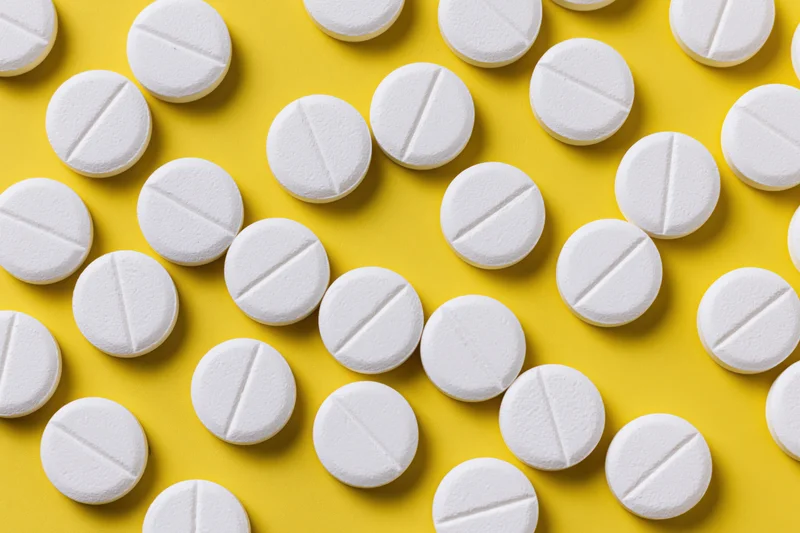 White round pharmaceutical tablets scattered on yellow background