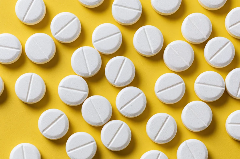 White round pharmaceutical tablets scattered on yellow background