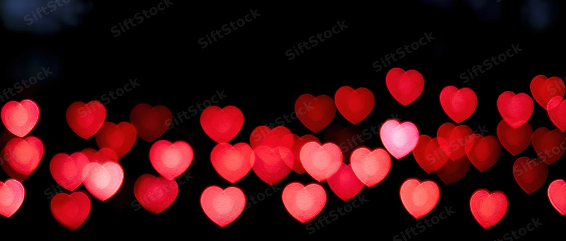 Heart-shaped bokeh lights glowing softly against a dark background