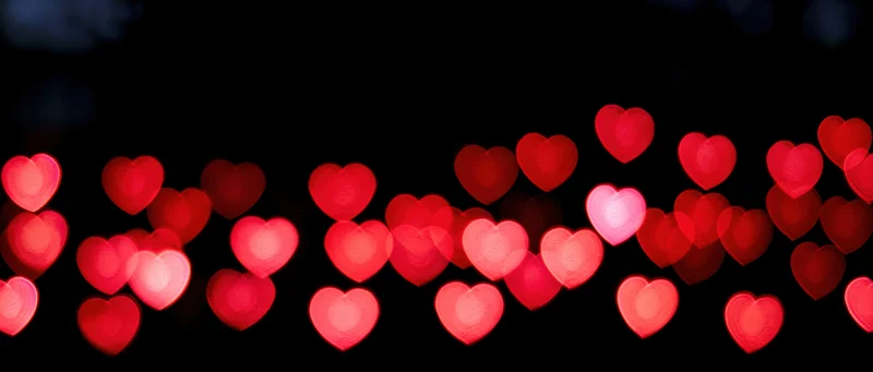 Heart-shaped bokeh lights glowing softly against a dark background