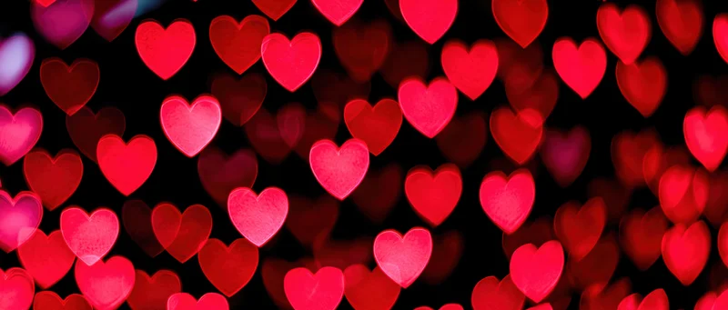 Soft out-of-focus heart-shaped bokeh lights filling the frame against a dark background