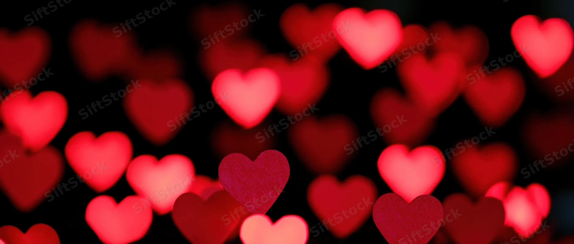Soft red heart-shaped bokeh lights glowing against a dark background