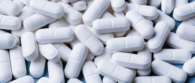 White oblong pharmaceutical tablets scattered loosely on a surface
