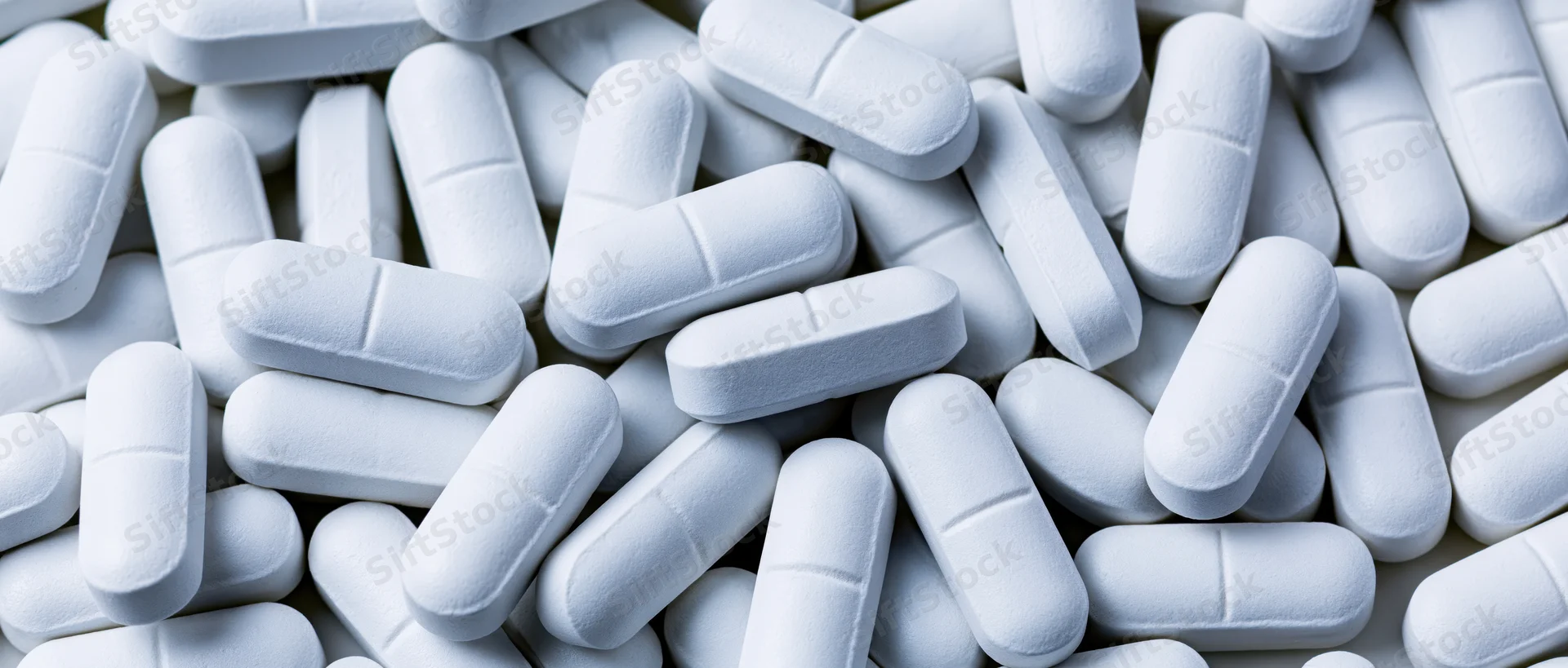 White oblong pharmaceutical tablets scattered in a pile