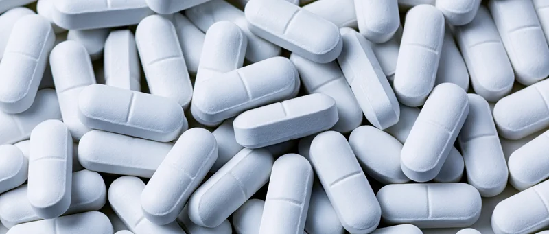 White oblong pharmaceutical tablets scattered in a pile