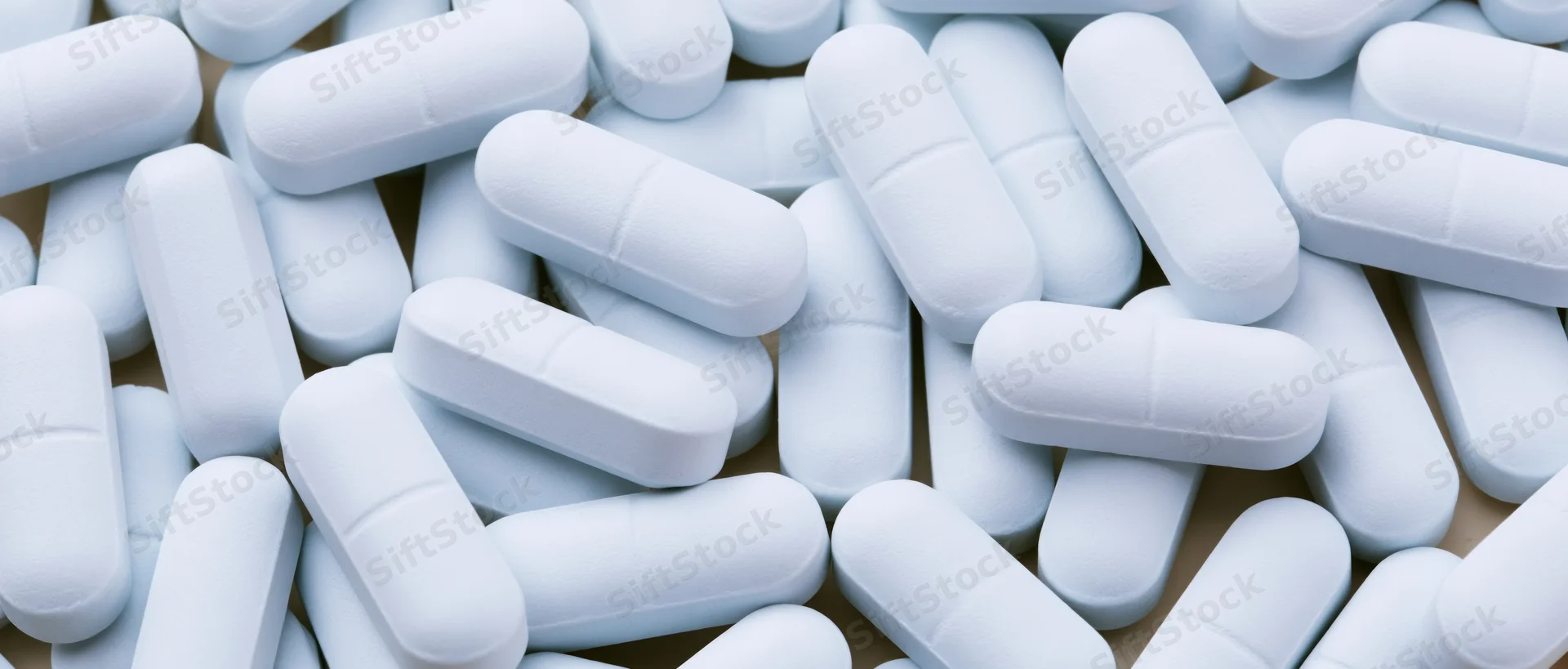 White oblong pharmaceutical tablets scattered loosely on a surface