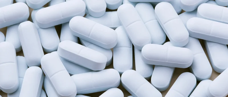 White oblong pharmaceutical tablets scattered loosely on a surface