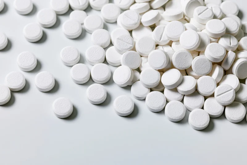 White round pharmaceutical tablets scattered on a light surface with copyspace