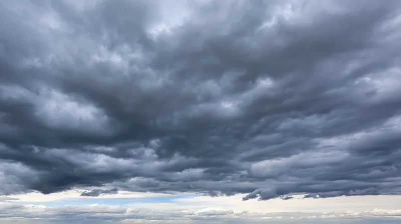Dark cumulonimbus clouds filling the sky above a distant horizon