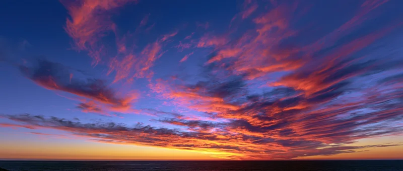 Dramatic sunset sky over ocean with vibrant clouds at twilight