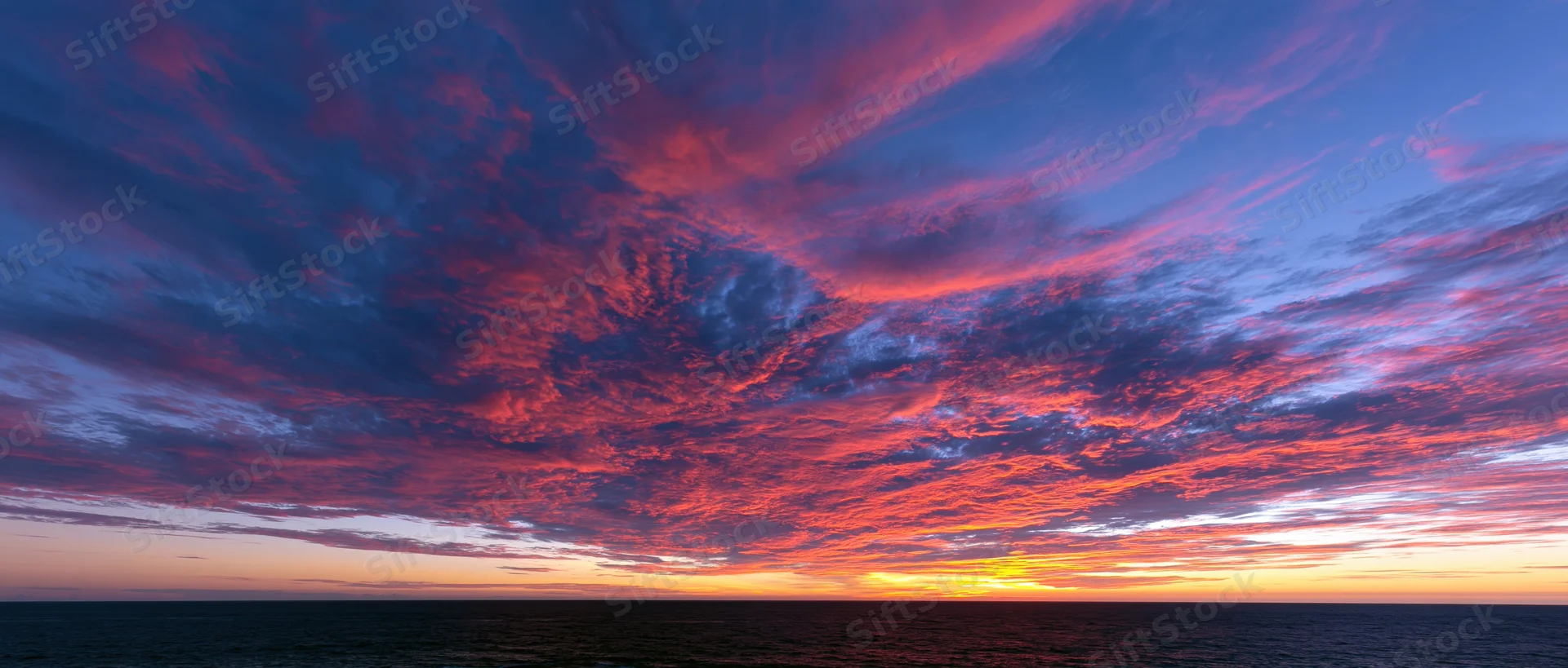 Dramatic sunset sky over the ocean with vibrant clouds at twilight