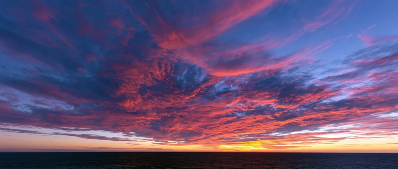Dramatic sunset sky over the ocean with vibrant clouds at twilight