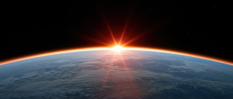 Earth's curved horizon from low orbit with sun rising directly over the planet's edge