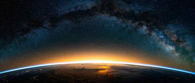Earths curved horizon from low orbit during golden sunrise with milky way above